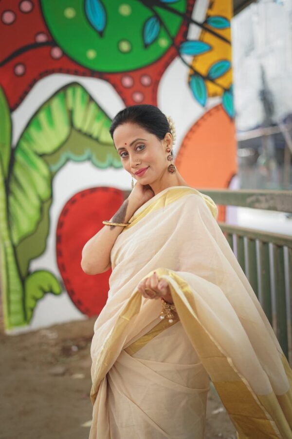 Elegant woman in a saree posing outdoors with a colorful mural backdrop.